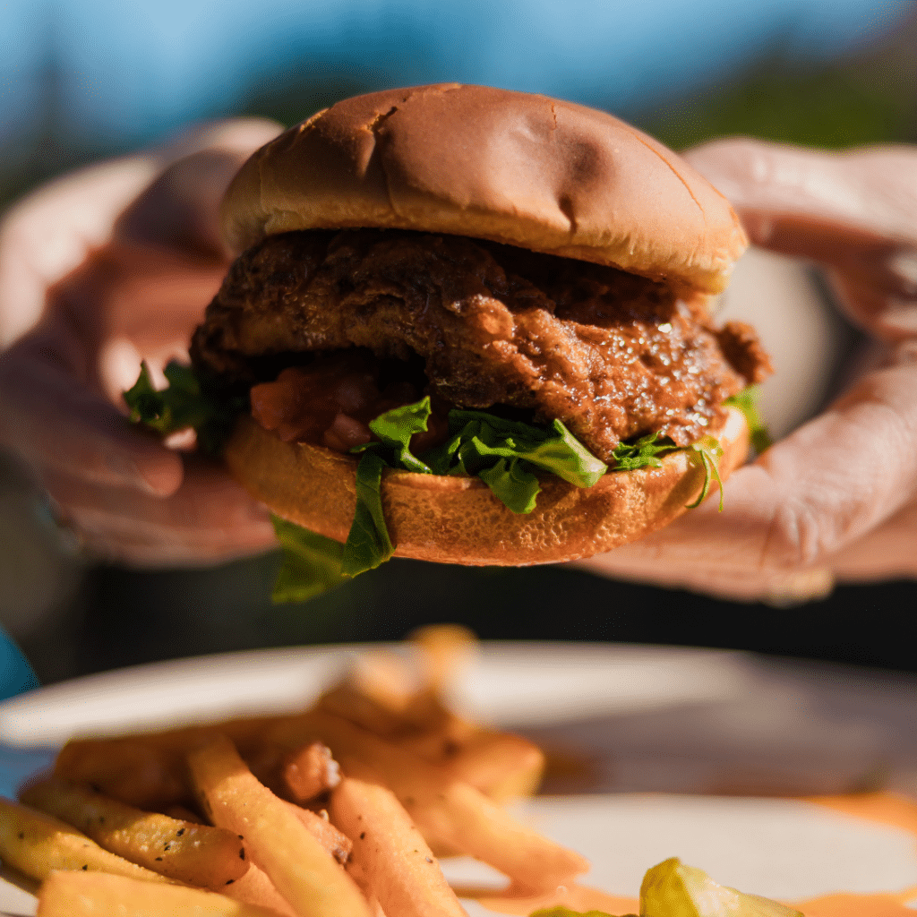 A closeup photo of a chicken sandwich with a side of fries.
