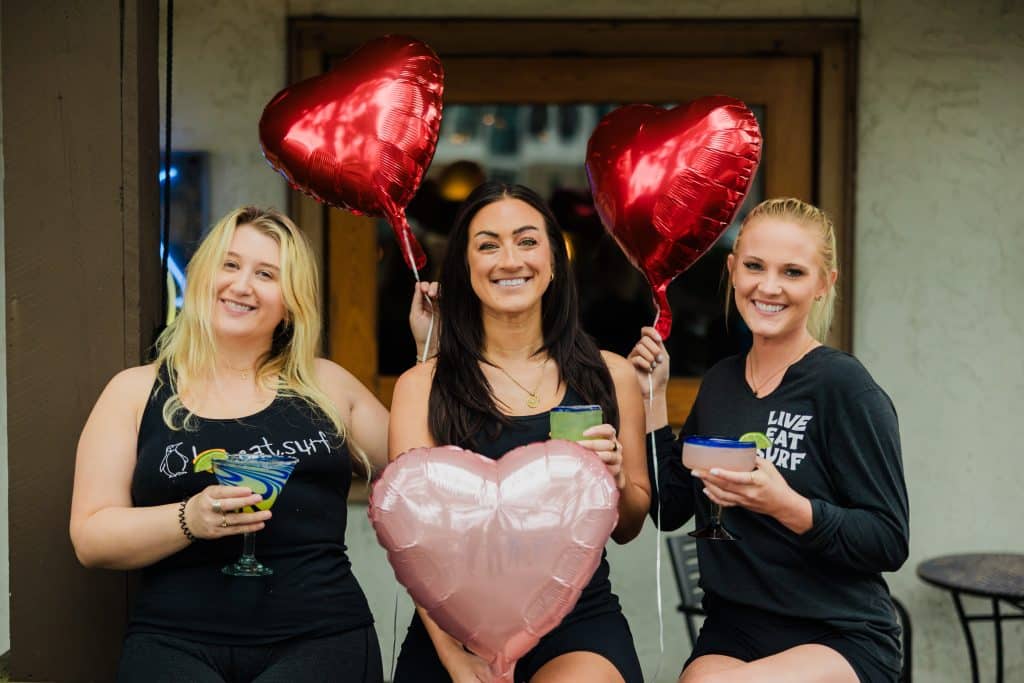 Staff holding heart-shaped balloons and margaritas.